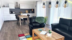 Ein modernes Wohnzimmer mit einer schwarzen Ledersofa, einem Holztisch und einem Essbereich mit einem Holztisch und Stühlen.
