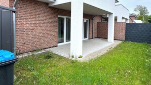 Ein modernes Haus mit Backsteinfassade, einer überdachten Terrasse und einer Schiebetür.