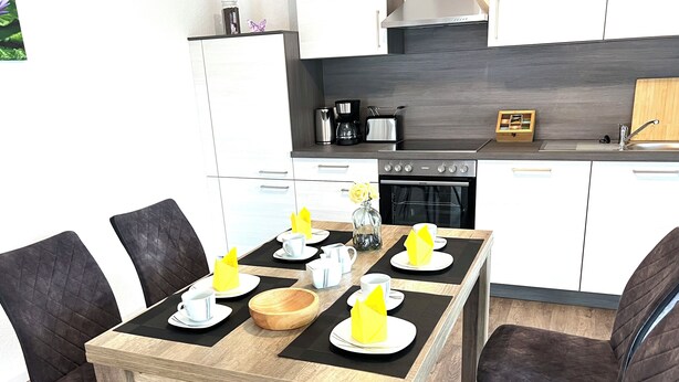 Eine moderne Küche mit Essbereich, ausgestattet mit einem Holztisch, Stühlen, einer Kaffeemaschine und einem Toaster.