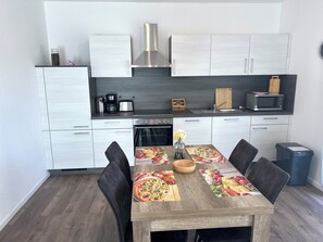 A modern kitchen with white cabinets, a stainless steel range hood, and a microwave on the countertop. - NEW "Nemo" Vacation Rental in Papenburg, Ground Floor, 83 sqm, 2 Bedrooms, Kitchen, Free WiFi, Terrace (Papenburg)