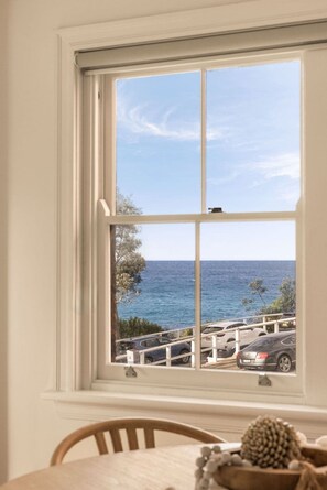 Ein Fenster mit Blick auf den Ozean und geparkte Autos.