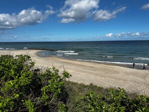 Ein Strand mit gewellter Küstenlinie, Wellen und blauem Himmel.