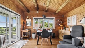 Un intérieur en bois comprenant un coin repas, un canapé et une vue à travers une porte vitrée.