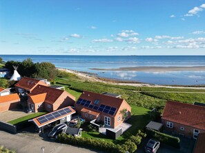 A residential area with houses, solar panels, and a beach view.