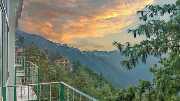 Un balcone con vista su un paesaggio montuoso e un tramonto.