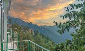 A balcony with a view of a mountainous landscape and a sunset. - The Wood Inn (Shimla)