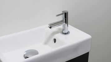 Un lavamanos blanco rectangular con un grifo cromado y un solo desagüe.