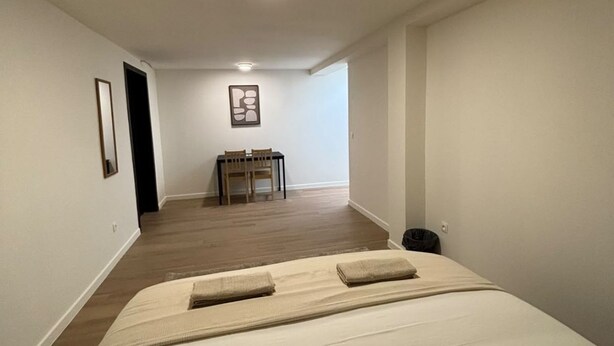 Ein Schlafzimmer mit einem Bett, einem kleinen Tisch und einem Stuhl im Hintergrund.