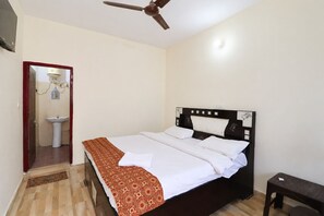 Un dormitorio con cama, ventilador de techo, mesita de noche y baño con lavamanos.
