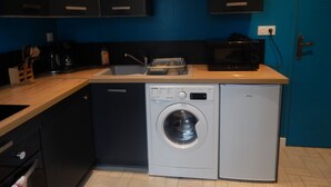 Une cuisine compacte équipée d’un lave-linge, d’un four à micro-ondes et d’un évier.