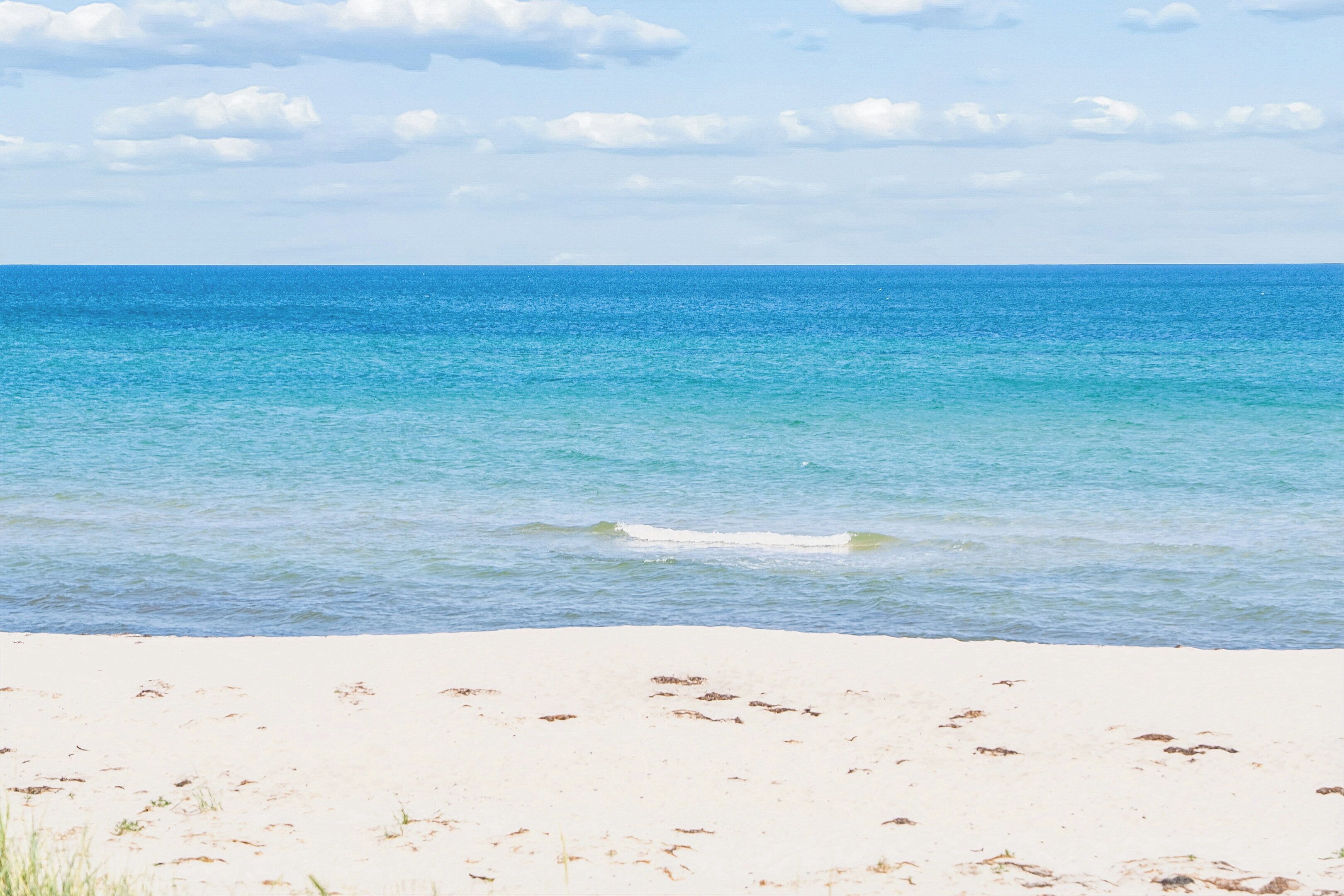A beach with clear blue water and a sandy shore.