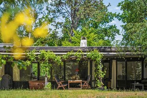 Eine rustikale Holzhütte mit überdachter Veranda, zwei Stühlen, einem Tisch und einem Schornstein.