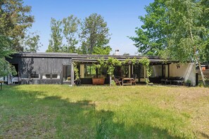 Eine rustikale Holzhütte mit Veranda, Essbereich und großem Fenster.