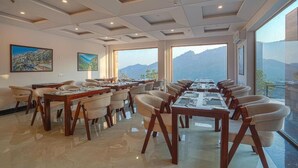 Uma sala de conferência com uma mesa comprida e cadeiras, janelas amplas com vista para as montanhas e obras de arte nas paredes.