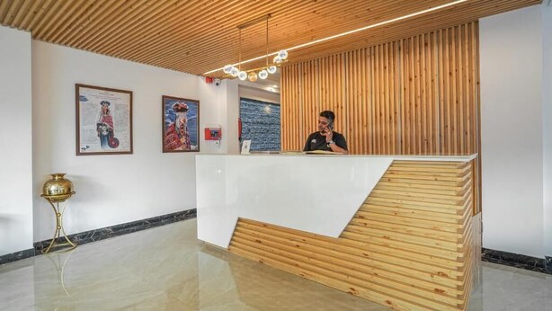 Uma área de recepção com um balcão de madeira, obras de arte emolduradas nas paredes e piso polido.