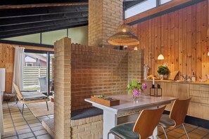 Une cuisine moderne avec des meubles en bois, une table à manger avec des chaises et une cheminée en briques.