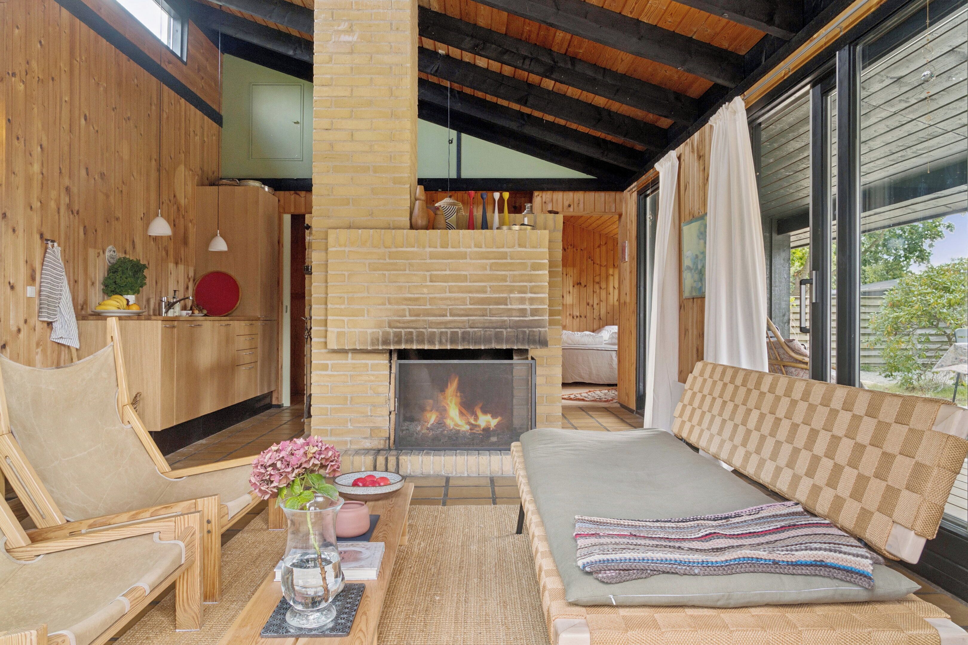A cozy living room with a fireplace, wooden furniture, and a view of the outdoors.