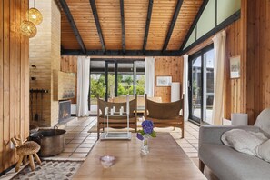 A modern interior with a wooden ceiling, a fireplace, a dining area, and a sofa. - Charming 70s retreat near beach and peaceful vibe (Odder)
