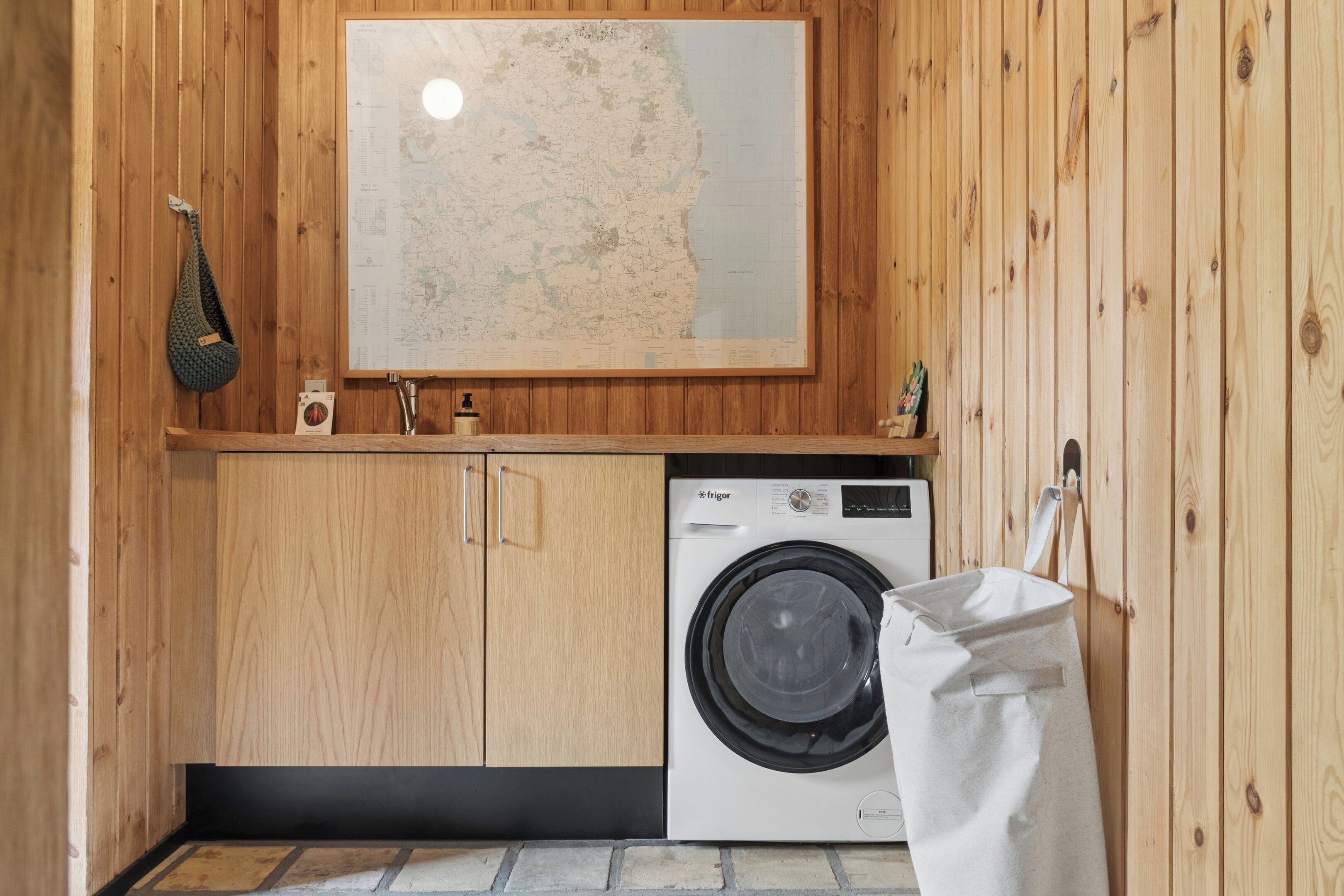 Un cuarto de lavandería con paredes de madera, una lavadora y un mapa en la pared.