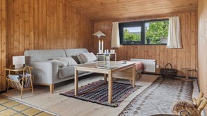 Una habitación acogedora con detalles de madera, un sofá, una mesa y una ventana con cortinas.