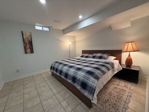 A bedroom with a bed, a nightstand, a lamp, a painting, and a ceiling vent. - Entire Privatesuite Separate Entrance Free Parking (Richmond Hill)