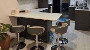 Una cocina moderna con una isla central, taburetes de bar y una planta en maceta.