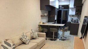 Una sala moderna con sofá, una mesa de centro y un comedor con taburetes de bar.