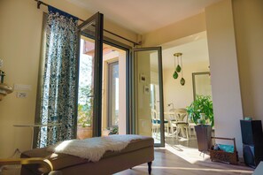 A room with a bed, a dining area, and a sliding glass door leading outside. - Villa Rodi - 3 Bedroom Holiday Home (Zakynthos)