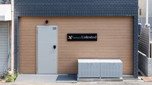 Un bâtiment moderne avec une façade en briques, un grand portail de garage et une enseigne indiquant « JAPAN VISTA Unlimited ».