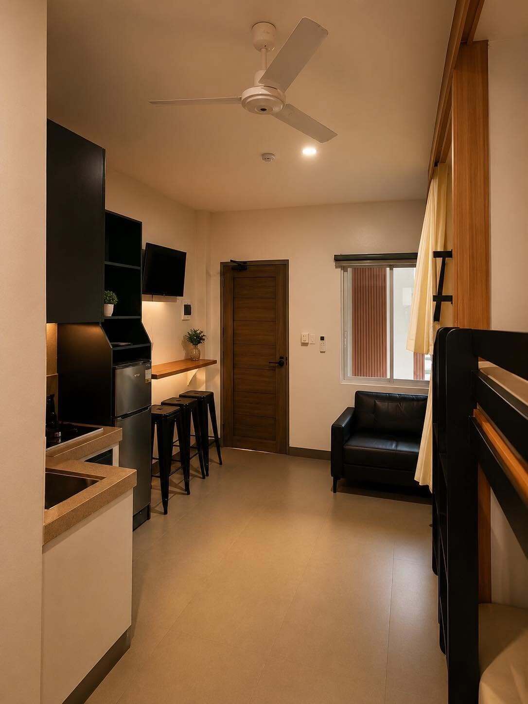 A compact living space with a kitchenette, a dining area, a sofa, and a ceiling fan.
