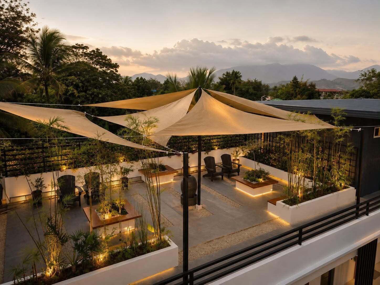 A rooftop terrace with outdoor seating, plants, and a view of mountains.