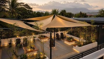 A rooftop terrace with outdoor seating, plants, and a view of mountains.