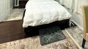 Un dormitorio con cama, mesita de noche, lámpara y un cuadro en la pared.