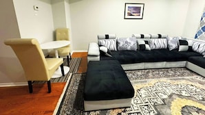Una sala de estar con un sofá modular, una mesita redonda y un sillón color arena.