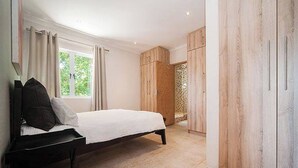 A bedroom with a bed, a desk, a wardrobe, and a window. - La Lucia Home With a View (uMhlanga)