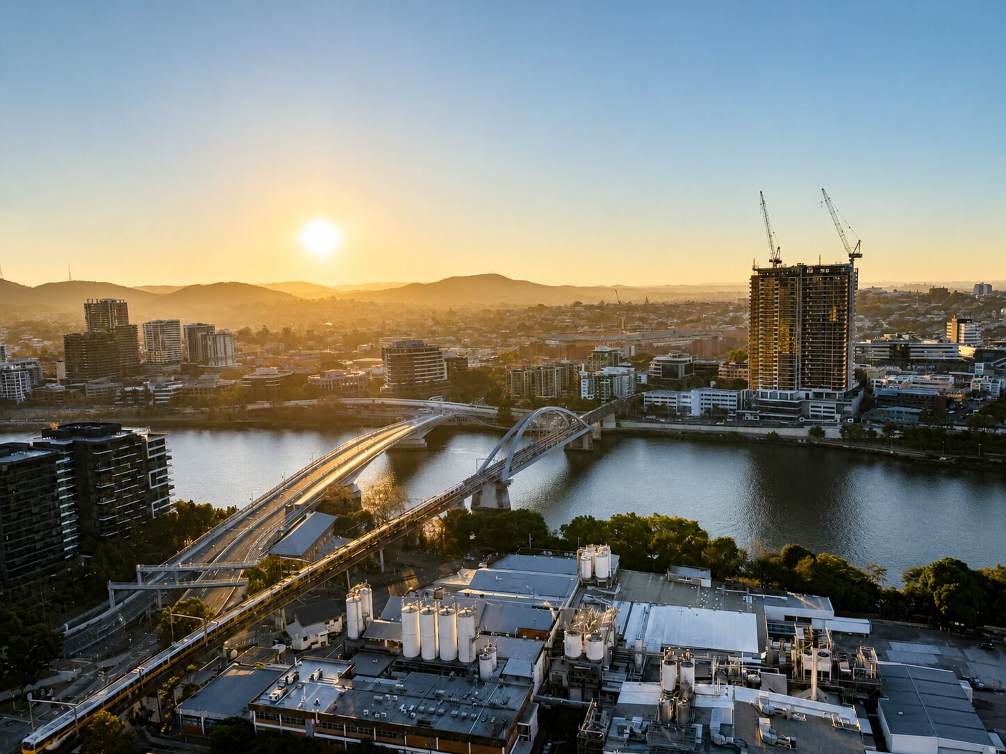 A cityscape with a river, a bridge, and a building under construction.