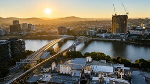 A cityscape with a river, a bridge, and a building under construction. - The Sunset Perch | Panoramic River Escape (South Brisbane)
