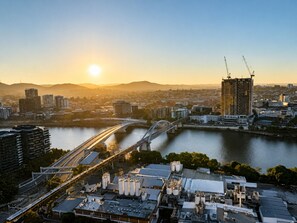 A cityscape with a river, a bridge, and a building under construction. - The Sunset Perch | Panoramic River Escape (South Brisbane)