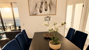 A dining area with a dark wooden table, blue chairs, white orchids, and a horse painting on the wall. - The Sunset Perch | Panoramic River Escape (South Brisbane)