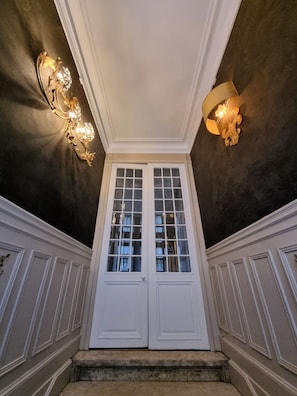 Uma entrada imponente com porta dupla, teto escuro e duas luminárias de parede.