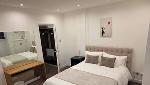A bedroom with a bed, a bench, a mirror, a wardrobe, and a painting on the wall. - Boutique Dairy Conversion Near Ilford Station (Ilford)
