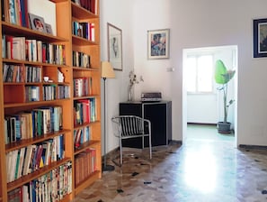 Une pièce comprenant une bibliothèque, une chaise, une lampe, un tableau et une plante en pot.