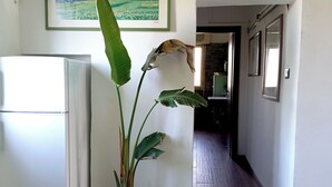A hallway with a potted plant, a refrigerator, and a framed painting on the wall. - A small villa nestled in the greenery of Rome (Roma)