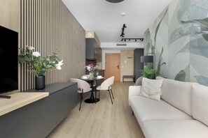 Ein modernes Wohnzimmer mit Flachbildfernseher, Essbereich und Sofa.
