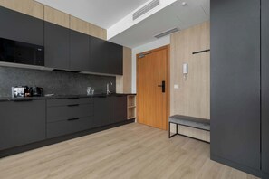 Eine moderne Küche mit dunklen Schränken, einer Holztür und einer Bank.