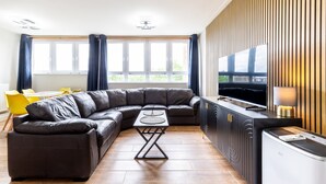 Una sala de estar moderna con un sofá modular, una mesa de comedor y un televisor.