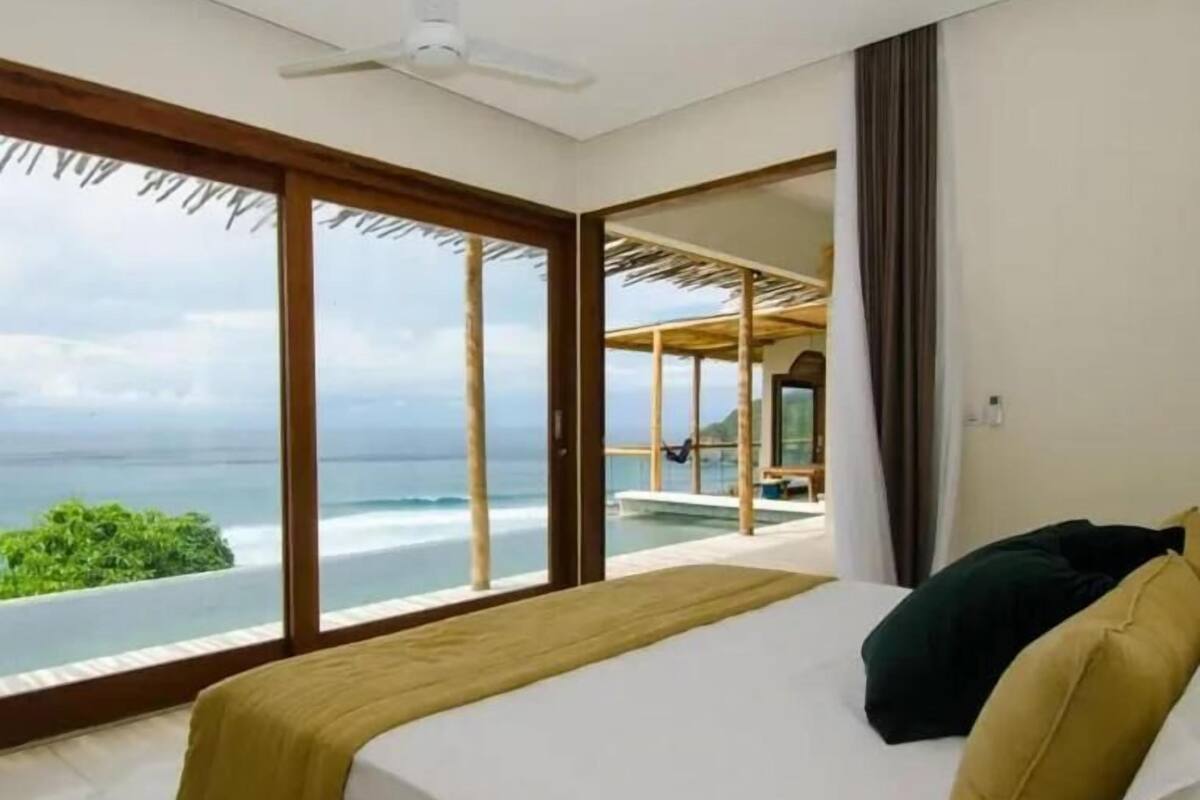 Ein Schlafzimmer mit Bett, Deckenventilator und Meerblick.