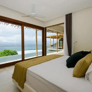 Ein Schlafzimmer mit Bett, Deckenventilator und Meerblick.