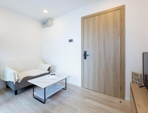 A room with a grey sofa, a white coffee table, a wooden wardrobe, and a television on a wooden stand. - チャオプラヤ川の絶景を望む高層階の心地よいお部屋 (Chang Wat Nonthaburi)