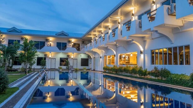 A modern hotel with a pool, multiple balconies, and a well-lit exterior. - Adela Resort Panglao (Panglao)